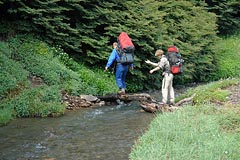 turisti, překonávají potok